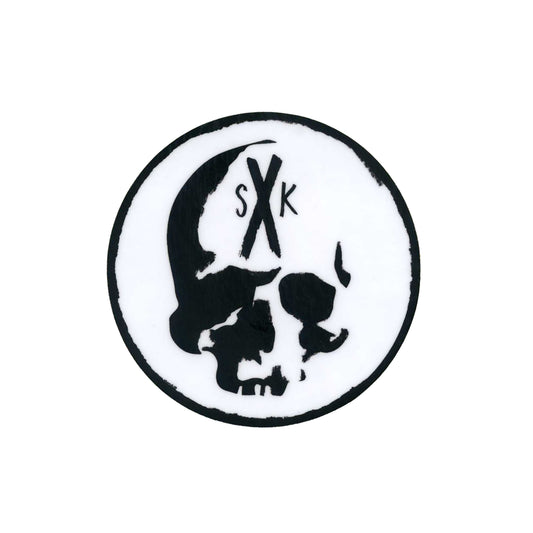 A circular black and white Sadistik logo displays a stylized skull. The letters S and K, separated by an X, appear above the skull within the circle.
