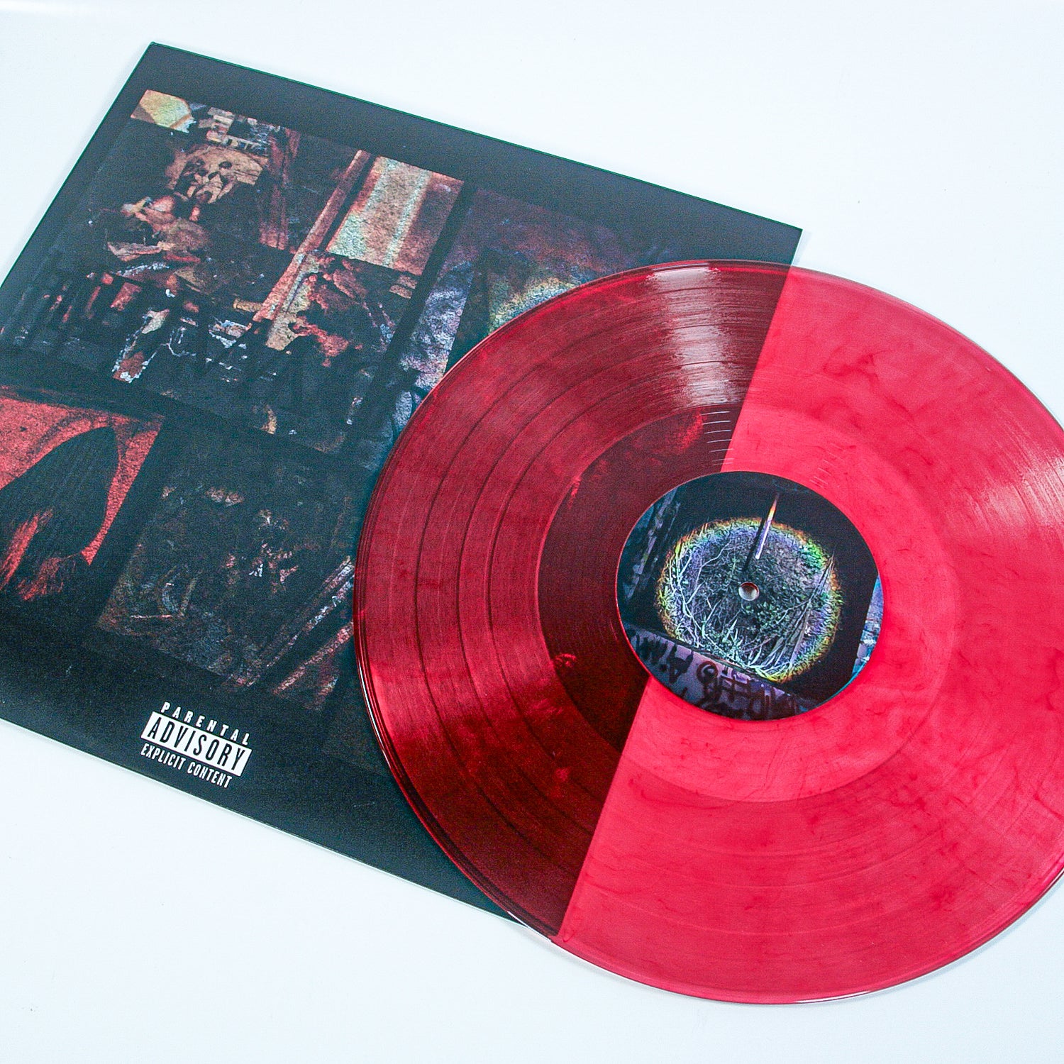 A marbled red vinyl by Sadistik partially rests on its album cover, which displays dark abstract art and a parental advisory label. This limited edition release stands out against the white background.